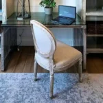 A sleek invisible home office setup featuring a modern desk with a laptop neatly integrated between two glass-door cabinets in a studio apartment.
