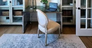 A sleek invisible home office setup featuring a modern desk with a laptop neatly integrated between two glass-door cabinets in a studio apartment.