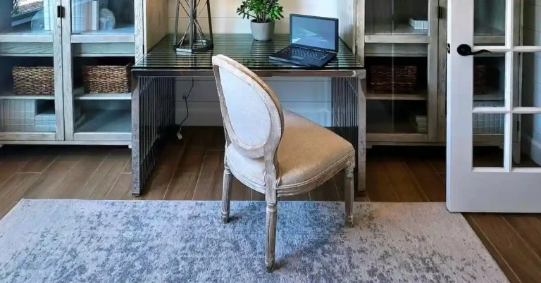 A sleek invisible home office setup featuring a modern desk with a laptop neatly integrated between two glass-door cabinets in a studio apartment.