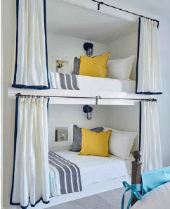 Built-in bunk bed solutions by Ashley Gilbreath showing a closet conversion with white privacy curtains and navy trim.