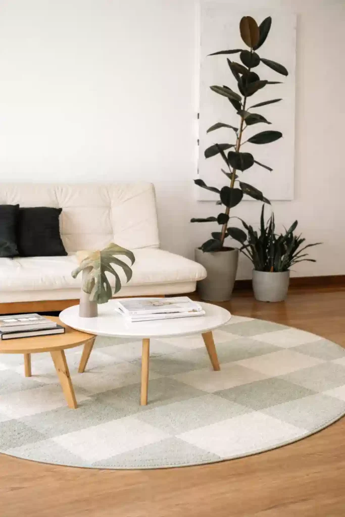 A round sage green checkerboard rug styled in a bright apartment, showcasing the best summer 2026 rugs for small spaces.