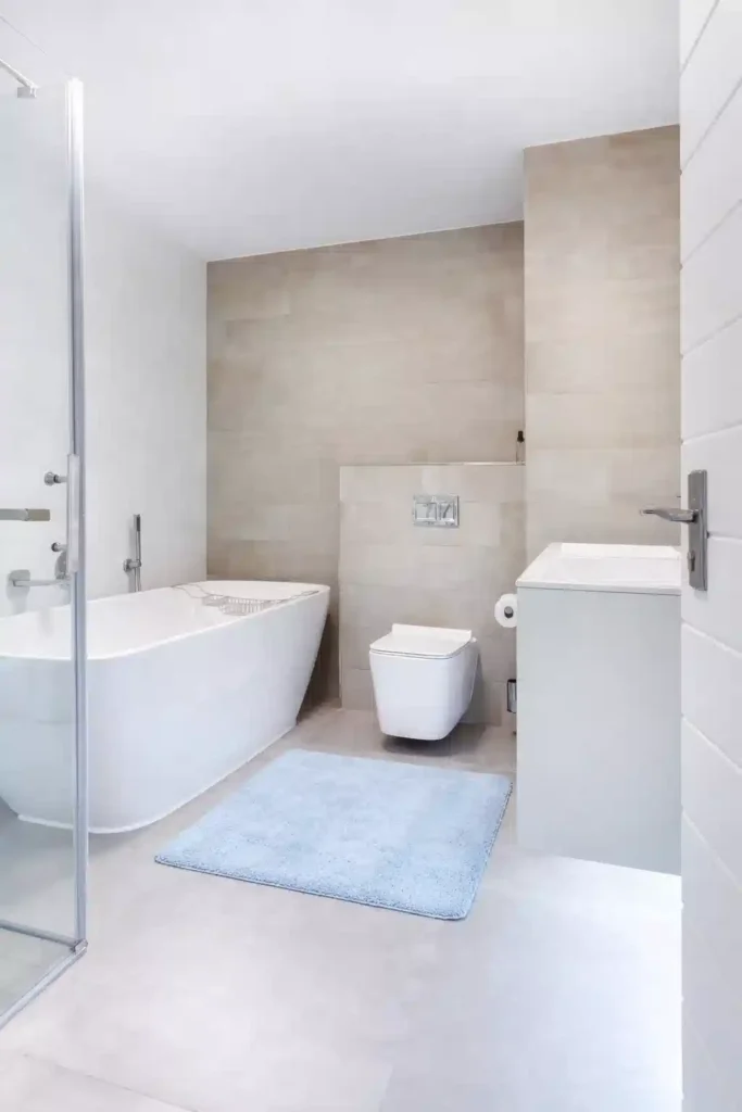 A plush sky blue cotton bath mat in a modern bright bathroom, featuring summer 2026 rugs for small spaces.