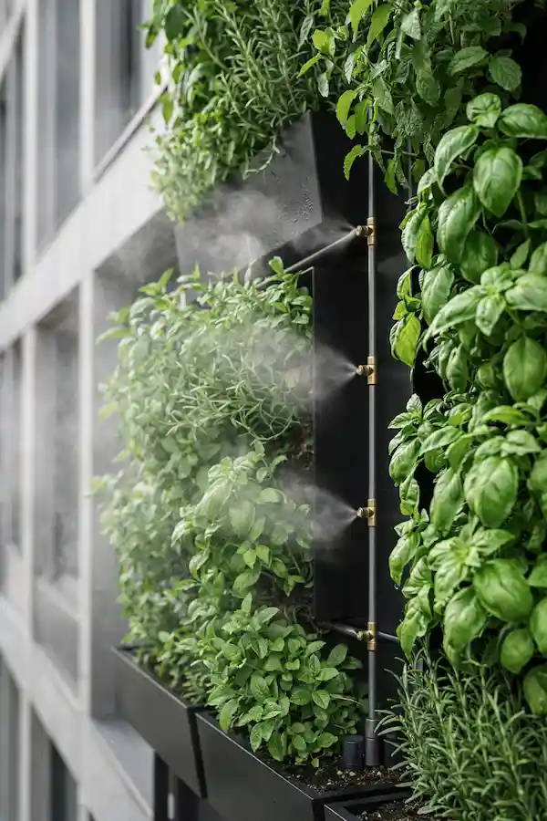 A vertical smart garden on a modern balcony featuring lush basil and mint with automated misting nozzles, illustrating smart balcony ideas 2026.