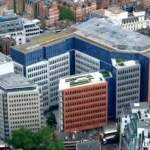 A high-angle aerial view of a modern colorful office complex designed for engineering the soundscape and optimizing urban acoustics in a busy city.