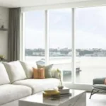 Modern small home decor 2027 trends featuring a bright living room with neutral sectional sofa and large windows
