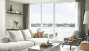 Modern small home decor 2027 trends featuring a bright living room with neutral sectional sofa and large windows